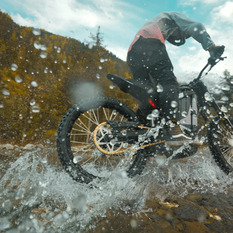 EUNORAU E-BIKE US R1-19 E-dirt bike outdoors, showing its rugged frame and off-road tires in a natural setting.